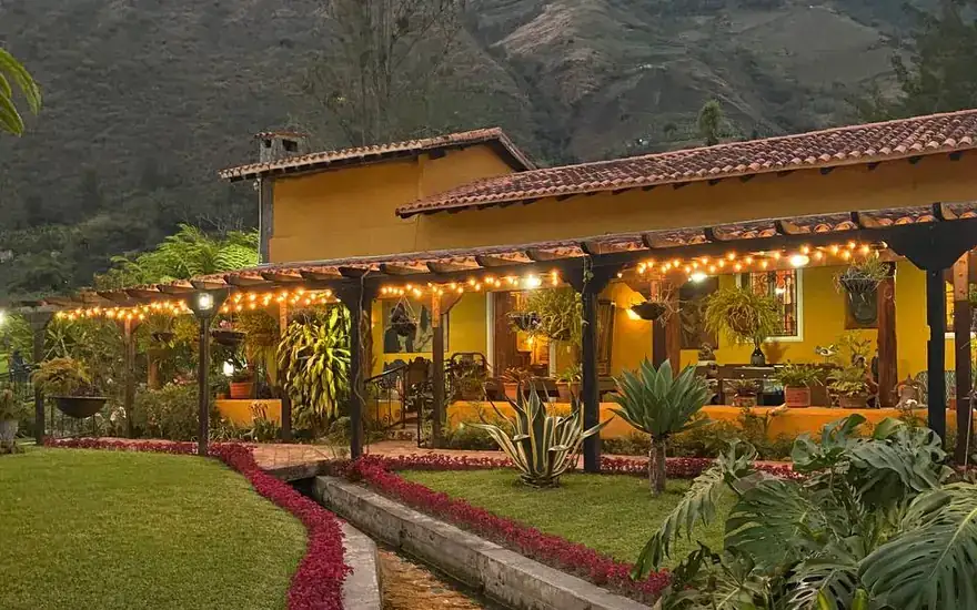 Hacienda El Rosario al atardecer, con sus jardines y la montaña al fondo